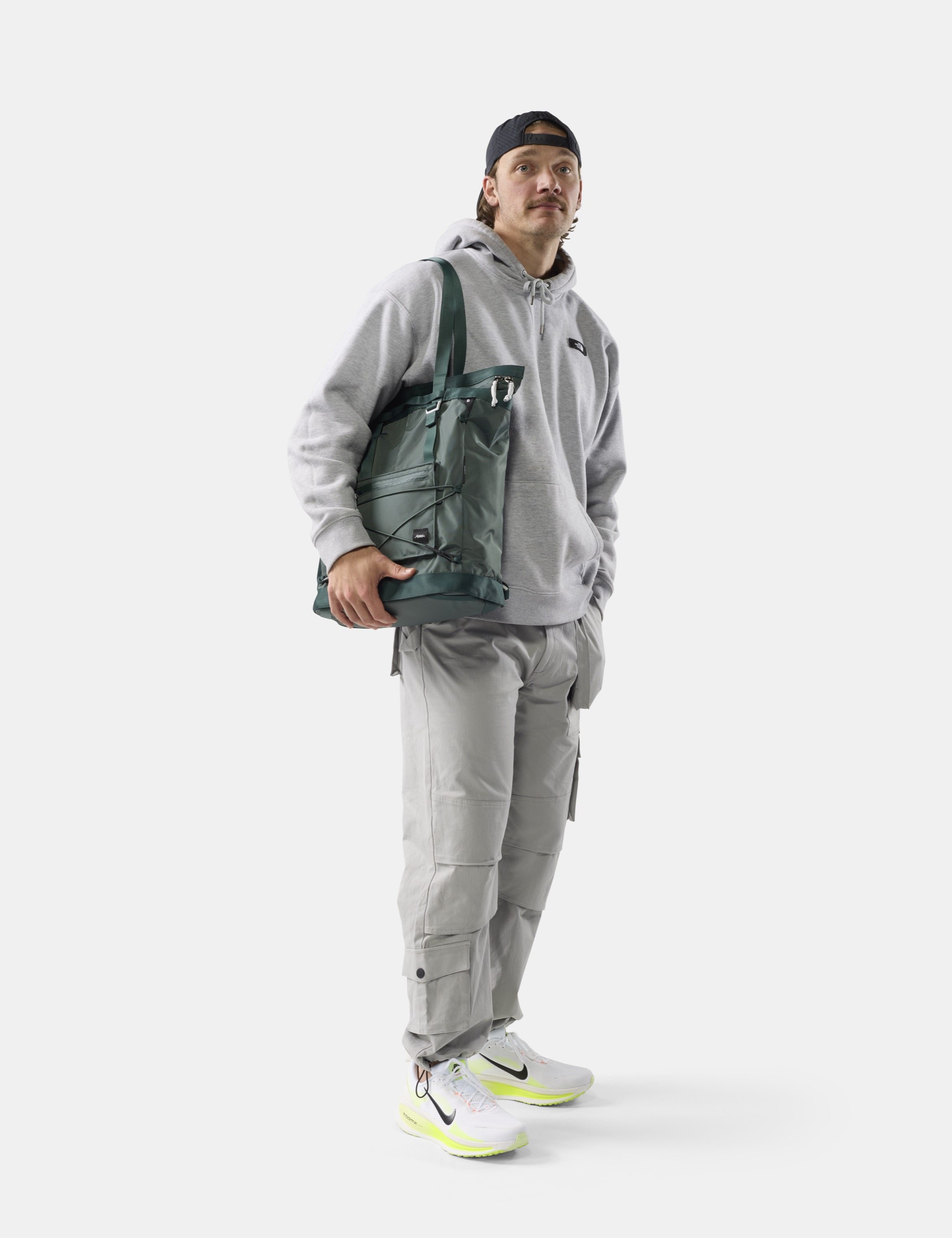 Grauer Hoodie, Tragetasche, Cargo-Hose, Sneaker, Baseballcap