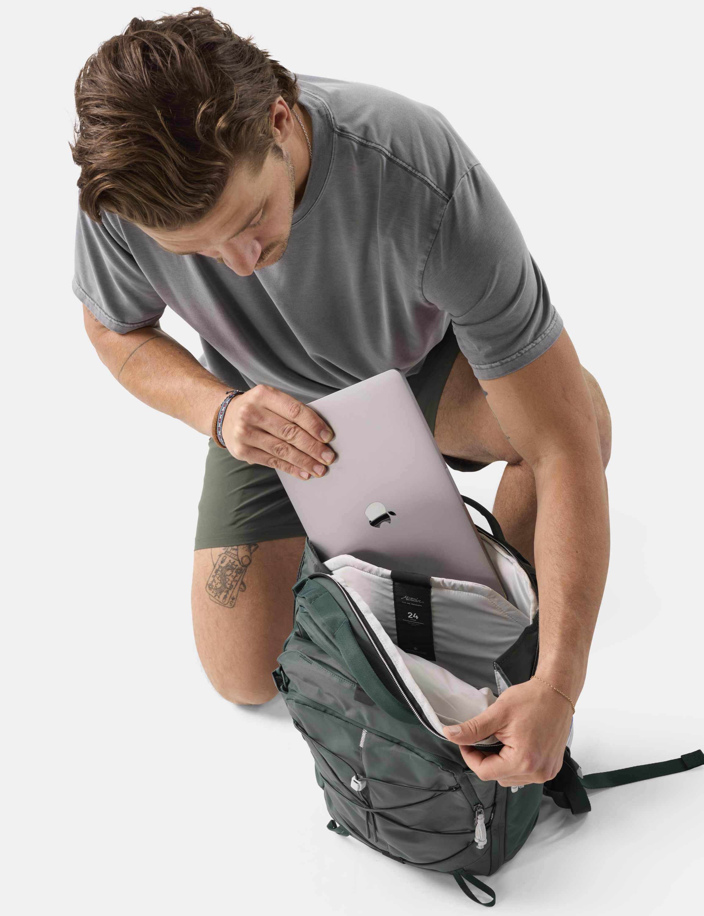 Rucksack, Laptopenfach, graues T-Shirt, grüne Shorts, Tattoo